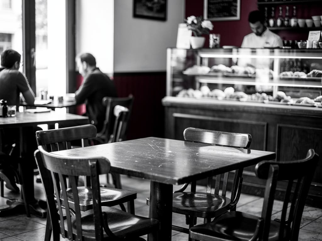 Interno accogliente della caffetteria con tavoli in legno e bancone dei dolci